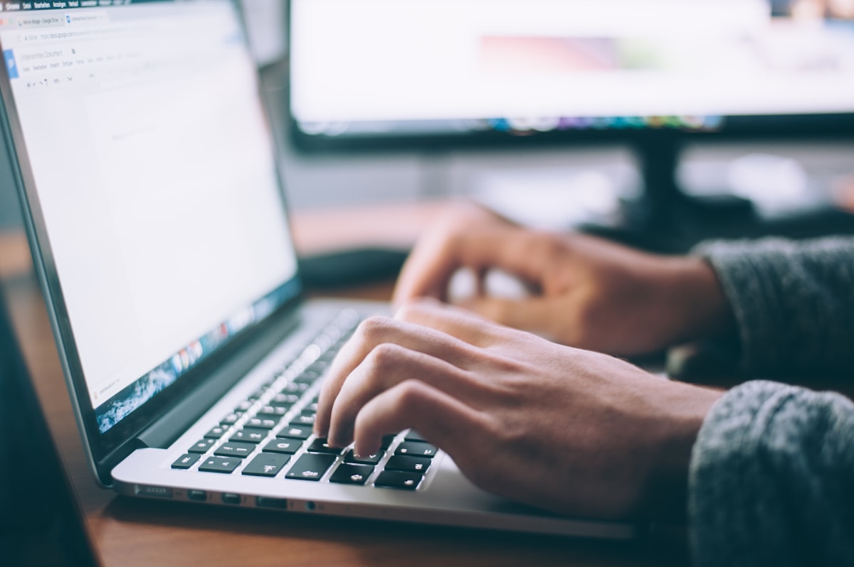 Person typing on a laptop at a clean desk setup