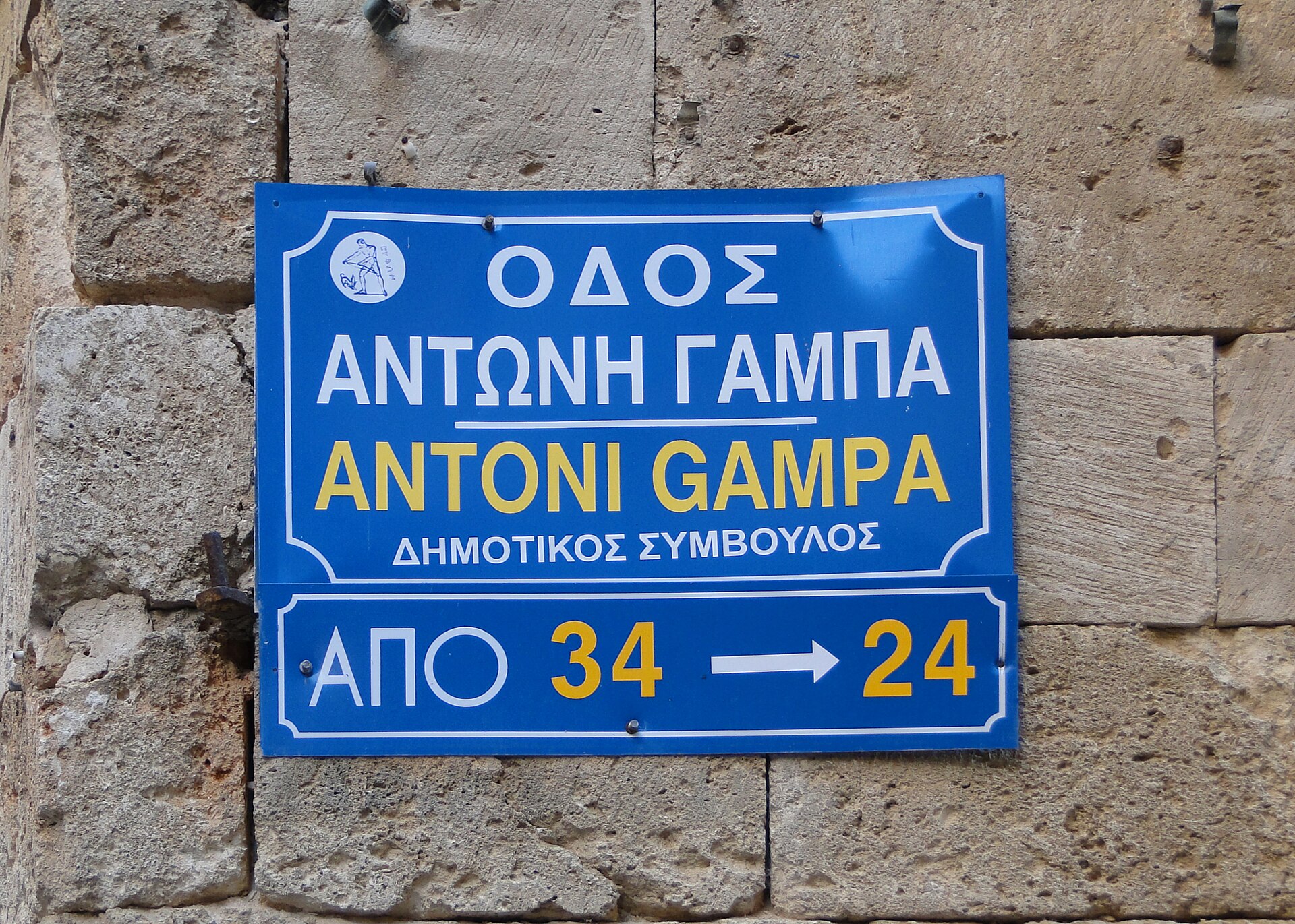 A street sign in Chania showing uppercase Greek text above a Latin-script transliteration