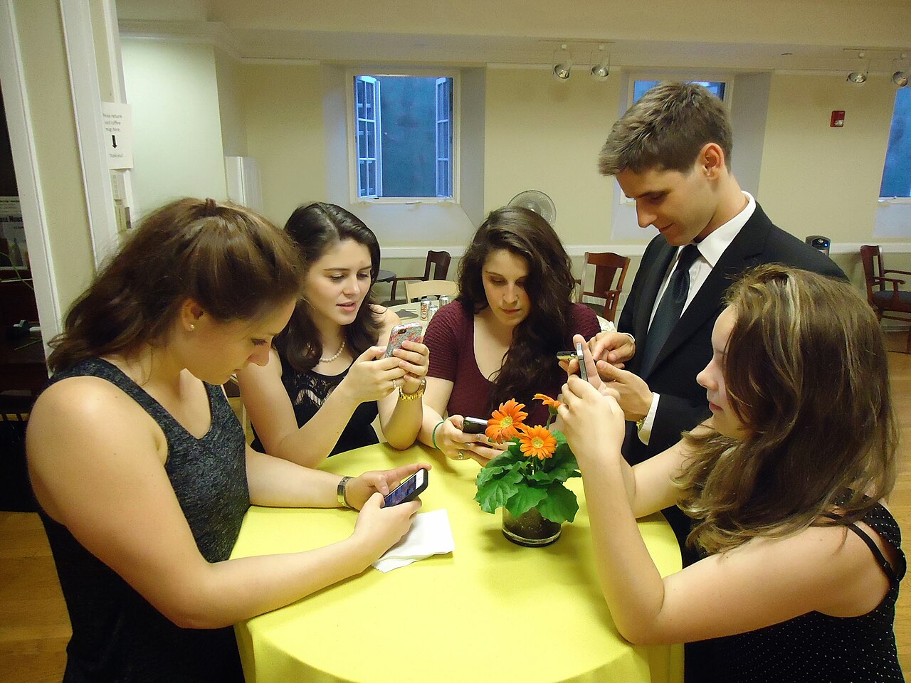 Young people texting on smartphones — Photo by Tomwsulcer, CC0, via Wikimedia Commons
