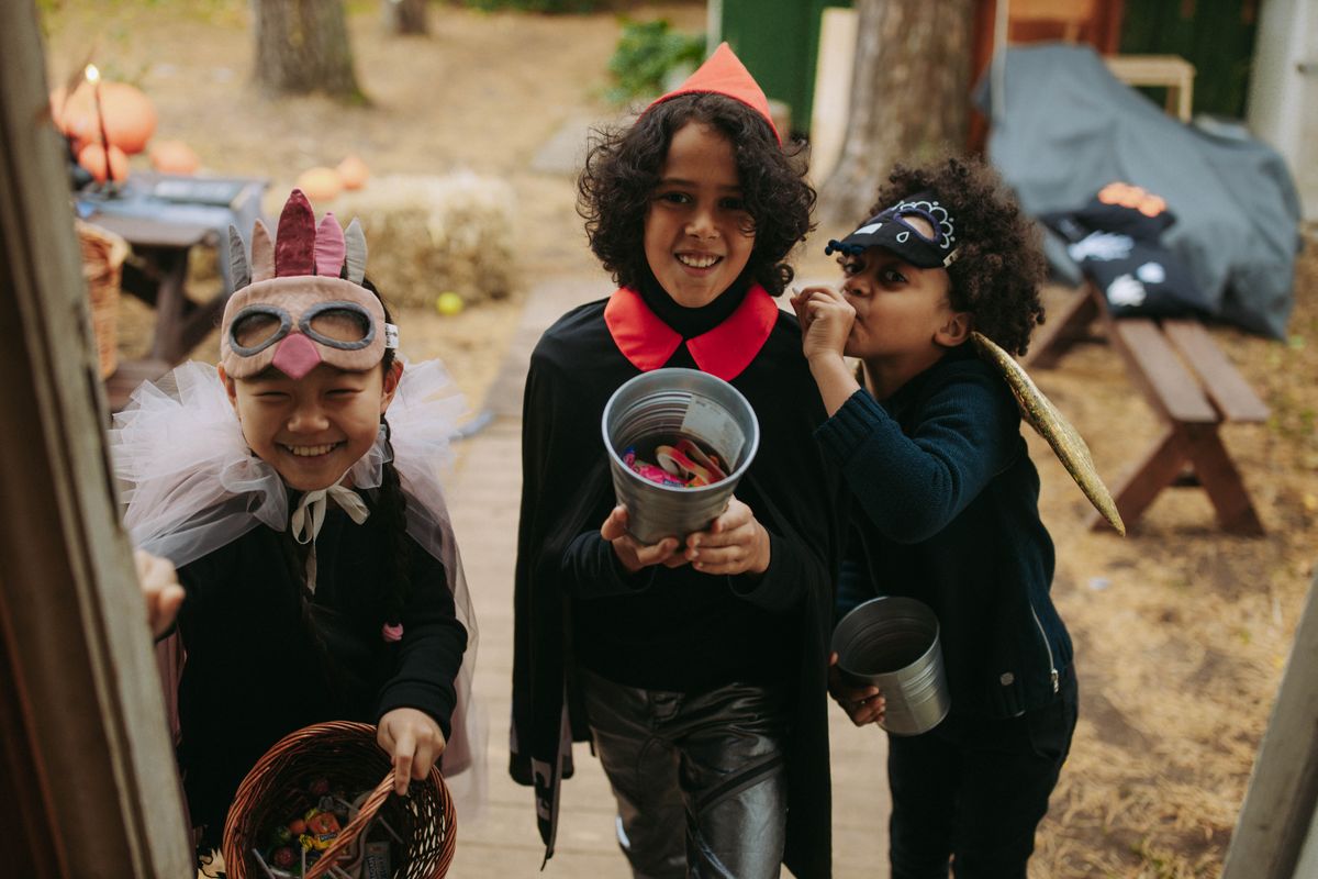 Children in Halloween costumes trick-or-treating with buckets