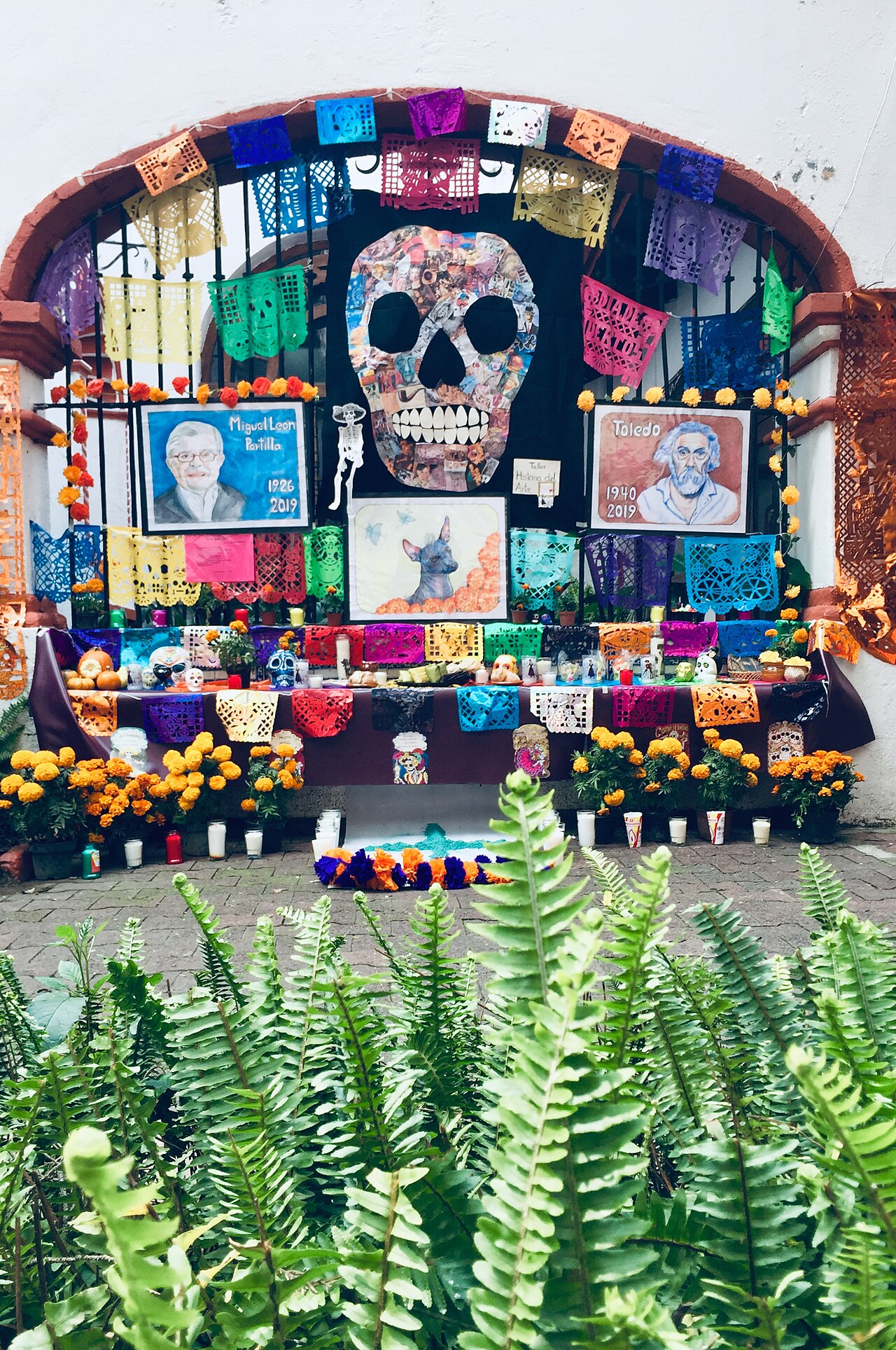 Outdoor Día de Muertos ofrenda with papel picado, marigolds, portraits, and offerings